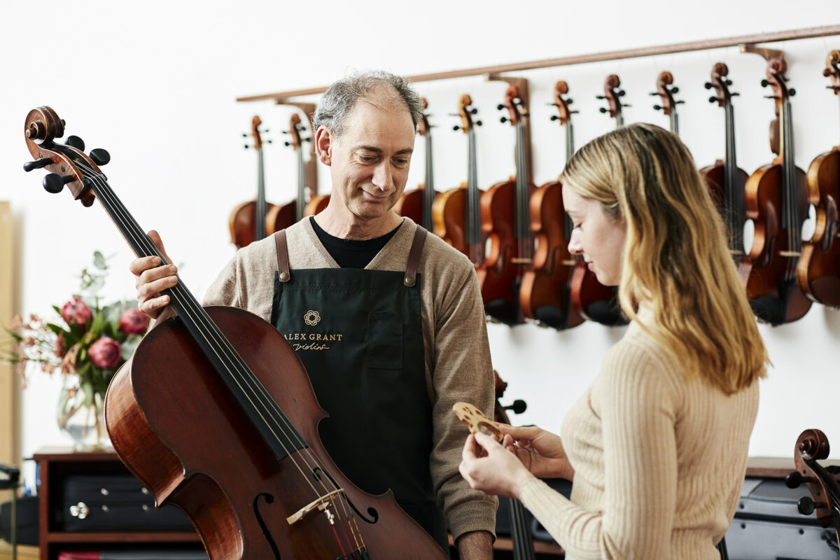 Violin makers at Alex Grant discusses cello bridge with a musician
