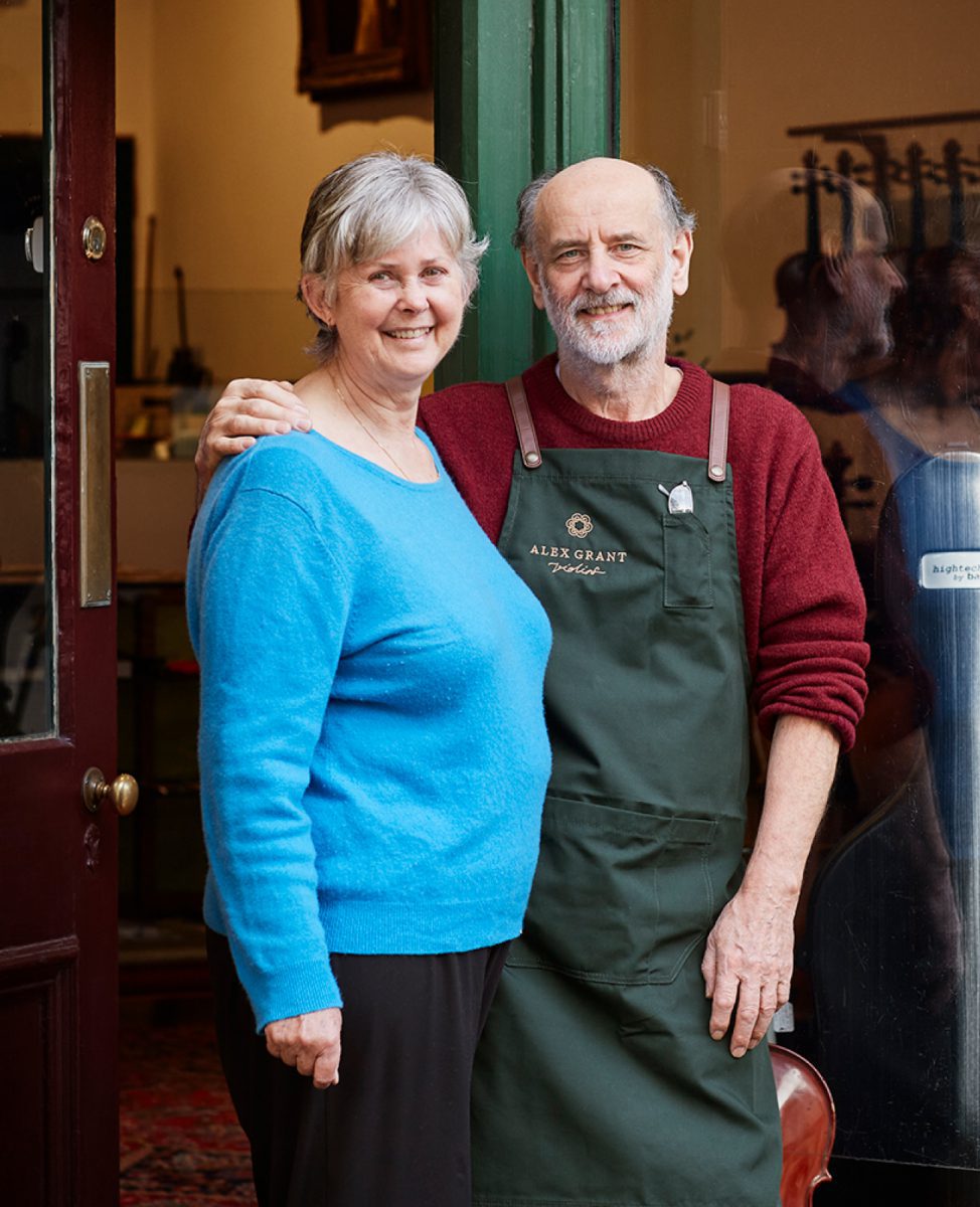 Marina and Alex Grant smiling in front of their Smith Street Violin Shop in 2022