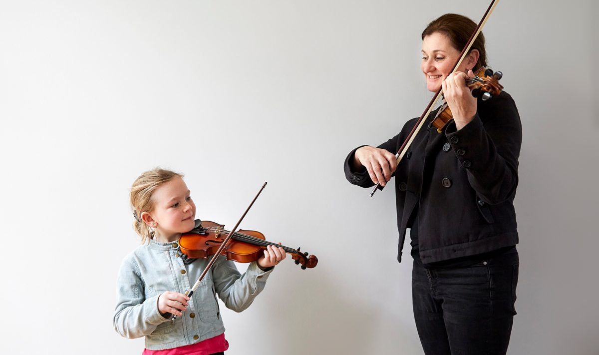 Student and teacher playing violin together
